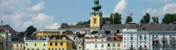 Gmunden, Rakousko: Město s kostelem, lodí a barevnými budovami na břehu jezera. Turistická destinace.