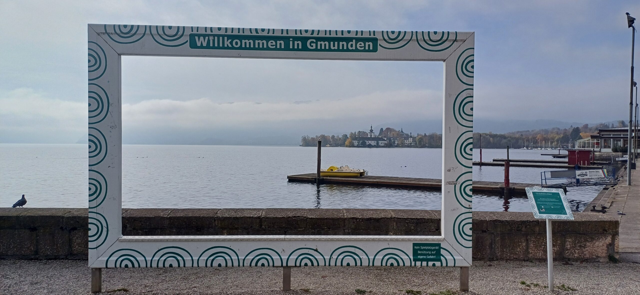 Podzimní Traunsee s barevnými lesy na břehu a klidnou hladinou jezera
