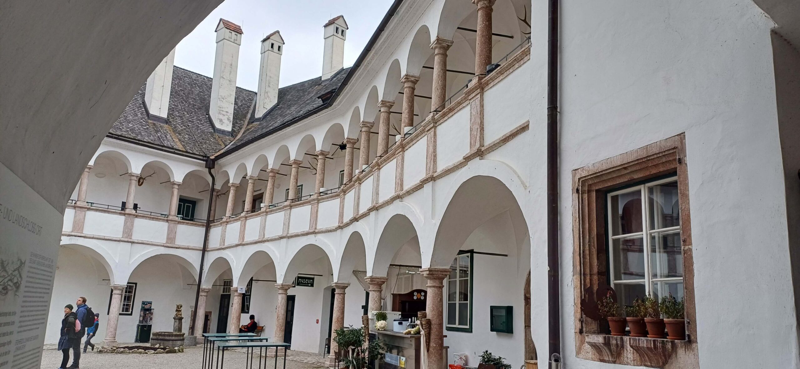 Renesanční arkádové nádvoří zámku s bílými zdmi, sloupy a sedlovou střechou. Architektura, historické památky a turistika.