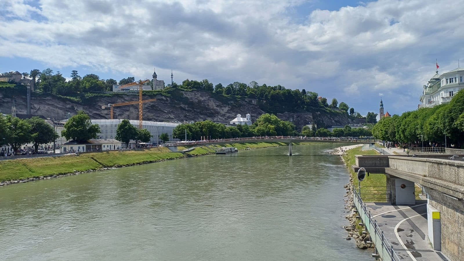 Pohled na řeku Salzach a staré město Salzburgu s kopci v pozadí