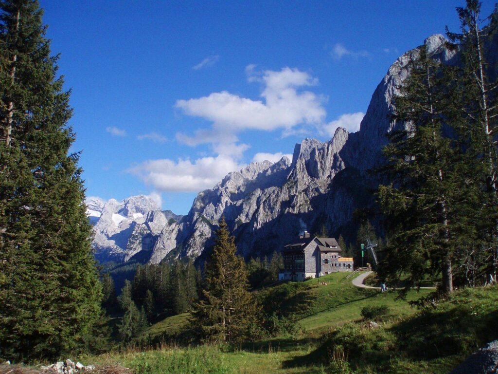 Chata Gablonzer Hütte na louce pod skalnatým Gosaukammem, vlevo ledovec Dachsteinu
