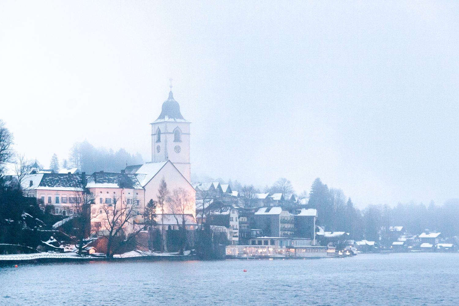 Obec St. Wolfgang s poutním kostelem nad Wolfgangsee v zimní mlze