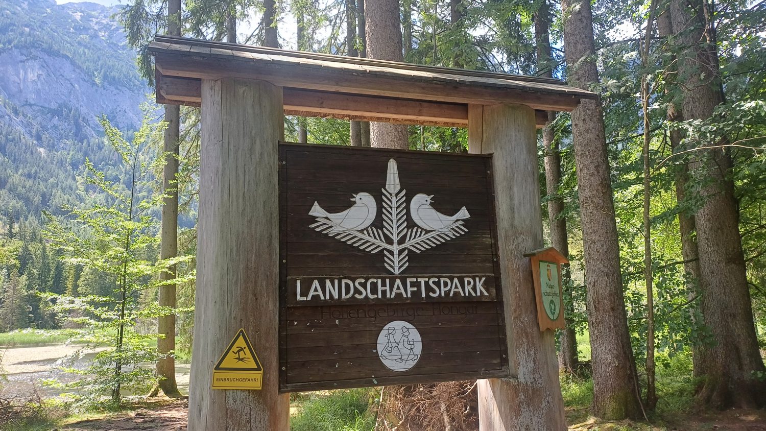 Dřevěná brána Landschaftspark Höllengebirge-Hongar se žlutým štítkem Einbruchgefahr u jezera