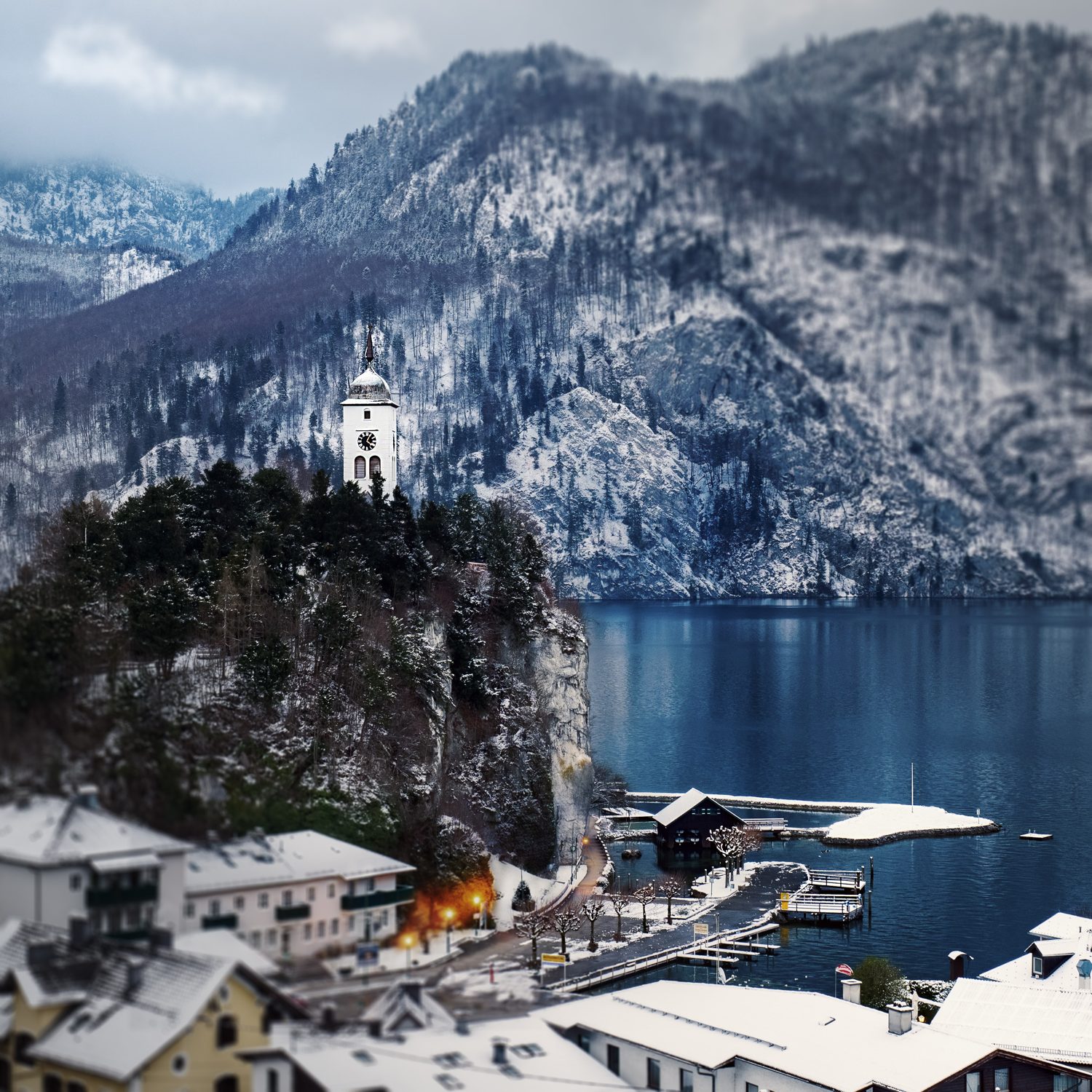 Traunkirchen v zimě: kostelík na Johannesbergu nad Traunsee a zasněžené střechy