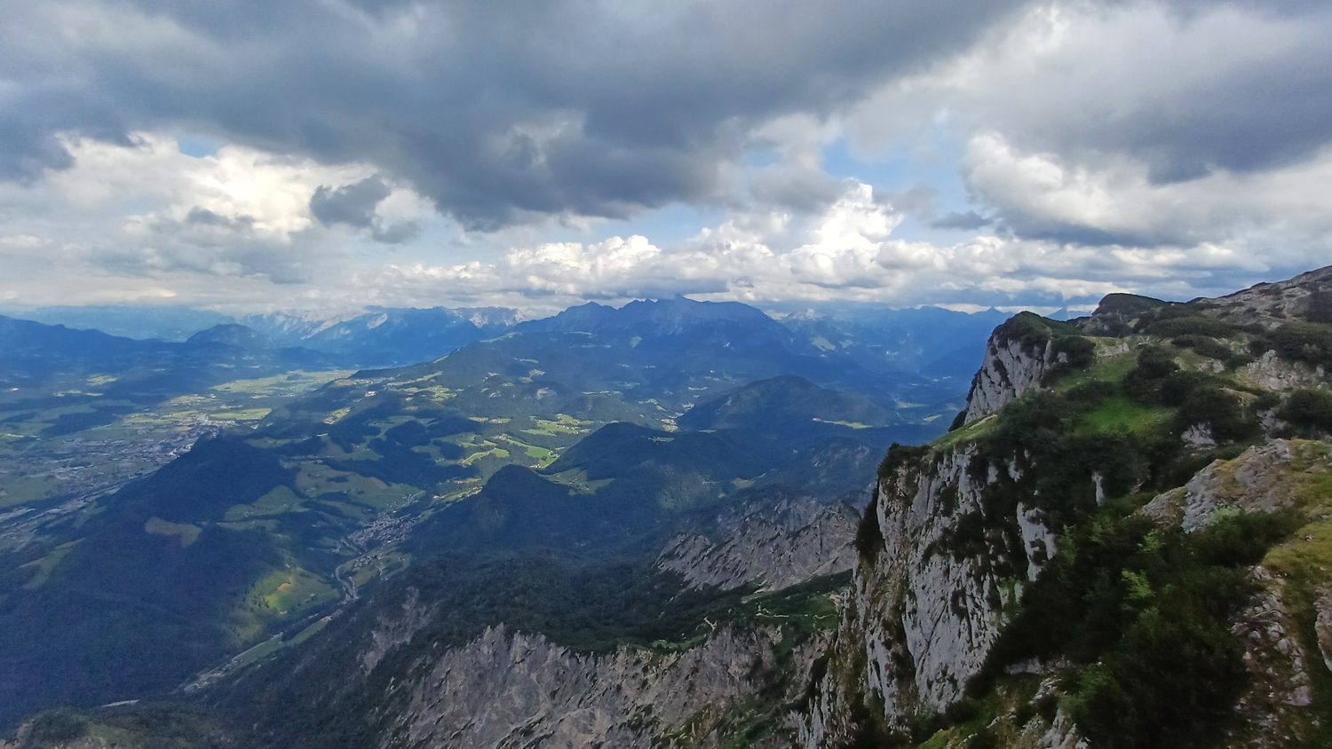 Hrana útesu Untersbergu nad zalesněnými údolími, nad horami těžké mraky