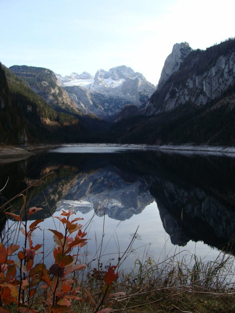 Vorderer Gosausee v listopadu se světlým pruhem obnaženého břehu, v hladině se zrcadlí Dachstein