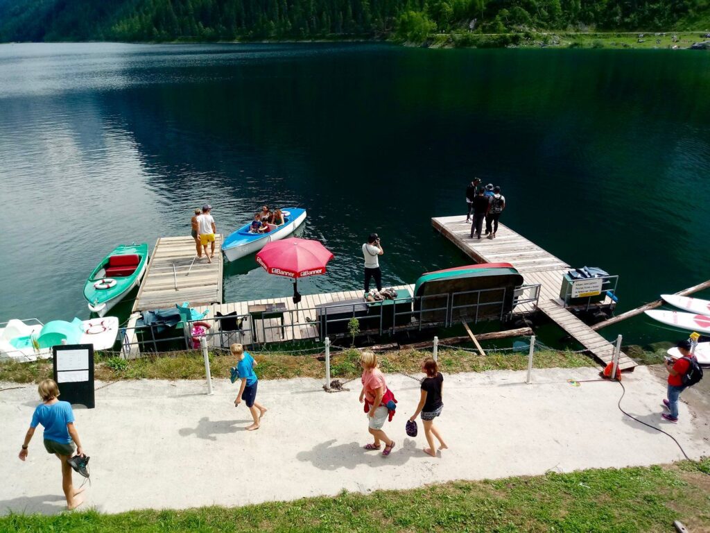 Molo s půjčovnou loděk na Vorderer Gosausee a lidé na břehu v létě