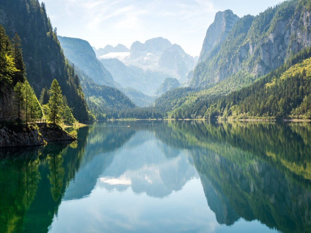 Dachstein a zalesněné svahy se zrcadlí v klidné hladině Vorderer Gosausee