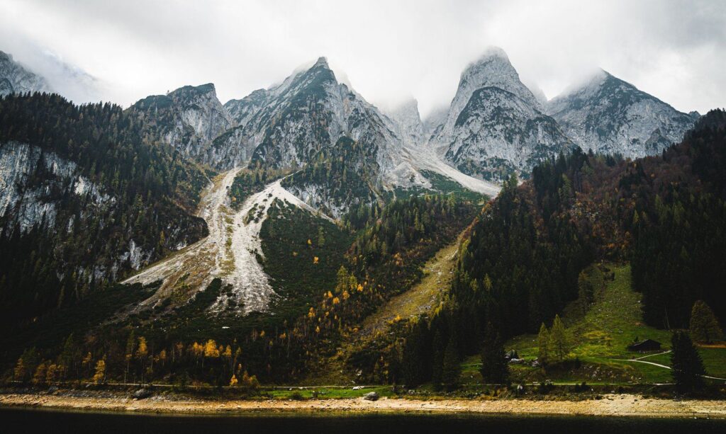 Gosaukamm s podzimním lesem nad Vorderer Gosausee, u vody pruh obnaženého břehu