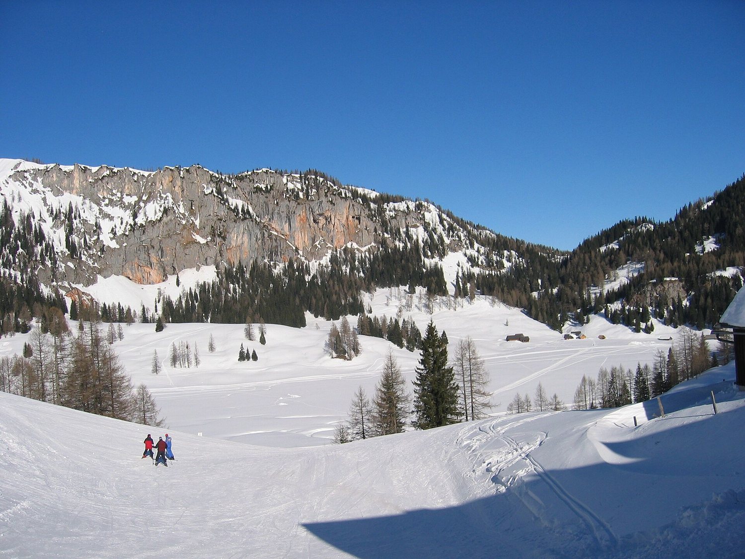 Lyžaři na Wurzeralmu pod skalními stěnami Totes Gebirge v únoru